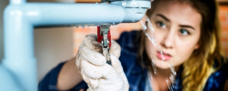 Vuotava hana jota nainen yrittää korjata. Valokuva.