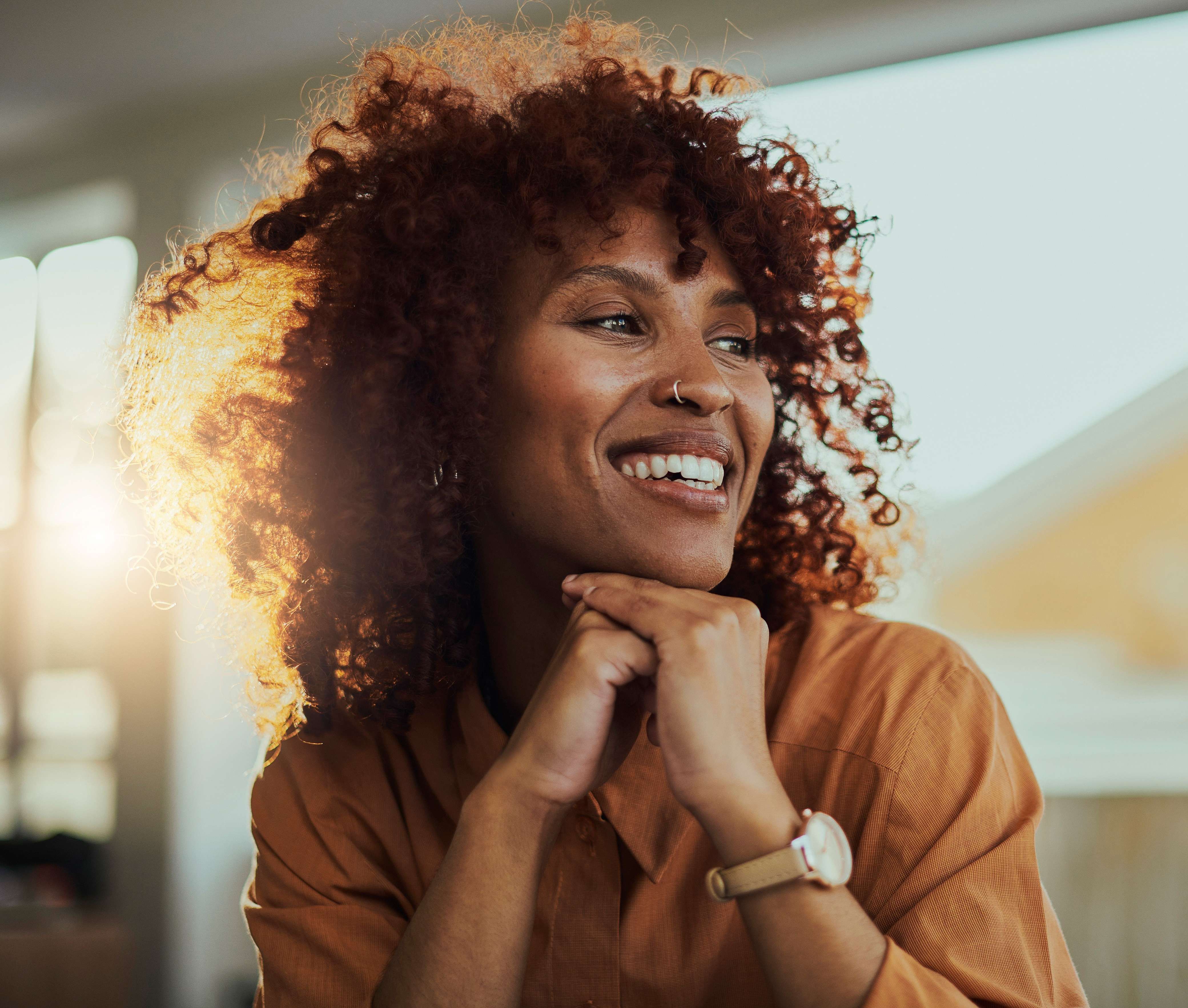 Jente med stort krøllete hår smiler og ser avslappet ut. bilde.