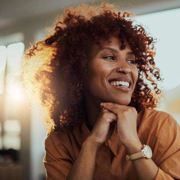 Jente med stort krøllete hår smiler og ser avslappet ut. bilde.