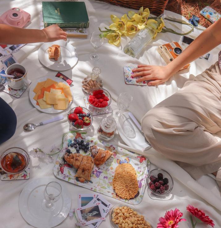 A white picnic blanket filled with colorful berries and biscuits