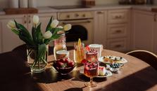 A kitchen table with white tulips and plates and glasses with juice and fresh berries
