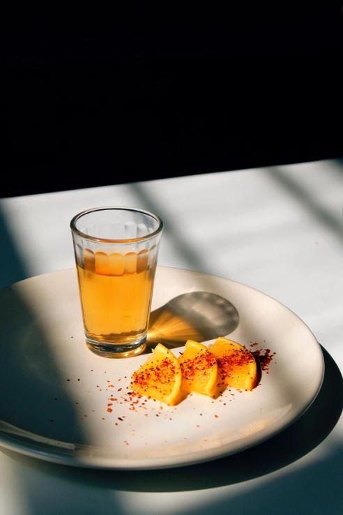 A plate with a glass of apple juice and oranges