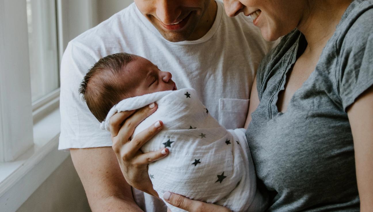 Parents with their newborn baby. They look happy.