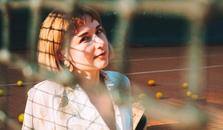 A woman is sitting on a tennis court in a white dress. It looks like there are tennis balls around her, but upon further inspection - they are apples.