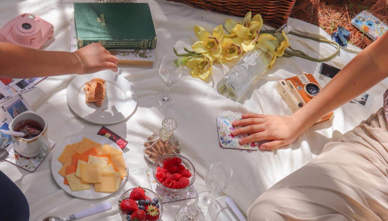 A white picnic blanket filled with colorful berries and biscuits