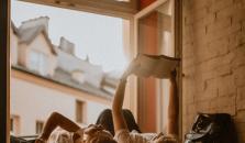 Two girls laying in a windowstill. One of the girls is reading a book.