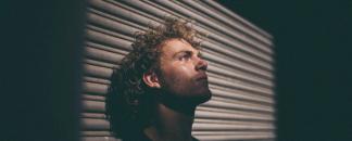 A man leaning onto a garage door and enjoying the sunlight