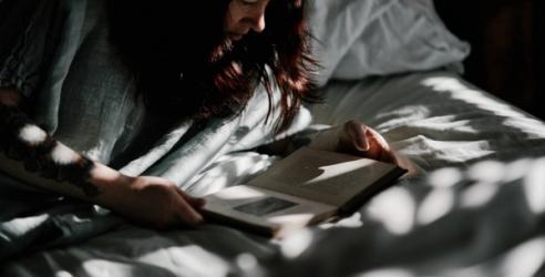A woman laying in bed reading a book