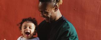 A man smiling and holding a child