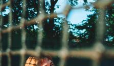 A woman is sitting on a tennis court in a white dress. It looks like there are tennis balls around her, but upon further inspection - they are apples.
