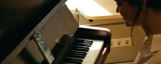 A girl in a white shirt playing piano