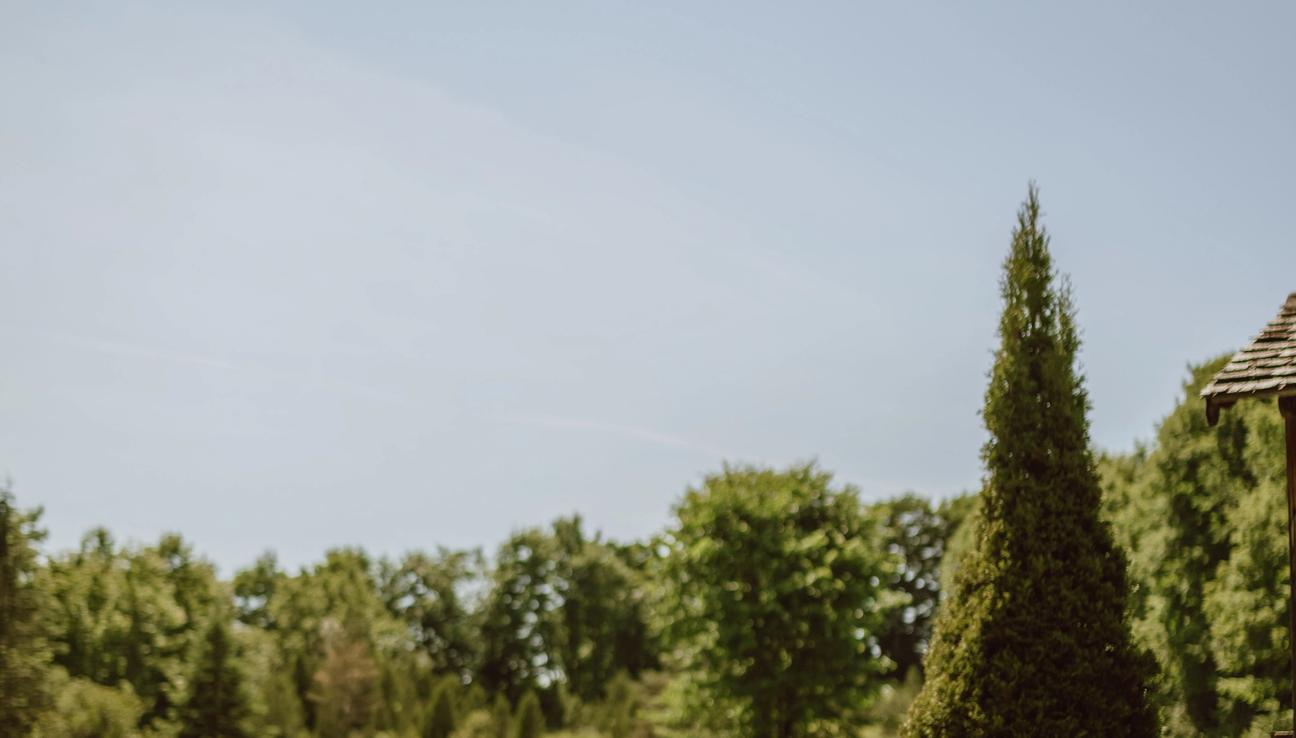 A girl with braids and a pretty dress, reading in a big grass field.
