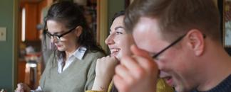 A group of friends is sitting around a table, eating and laughing.