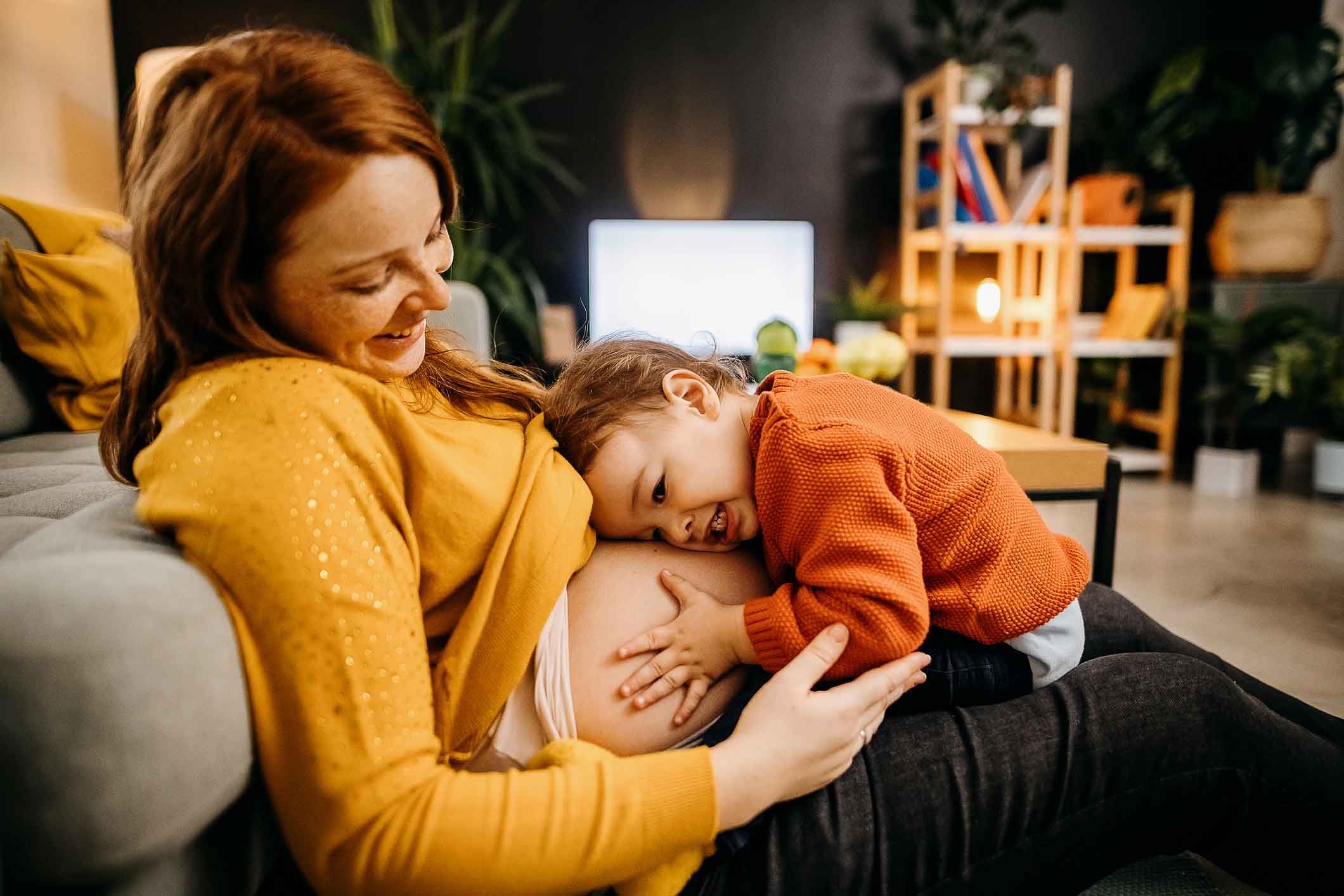 Toddler resting his head on mum's pregnant belly