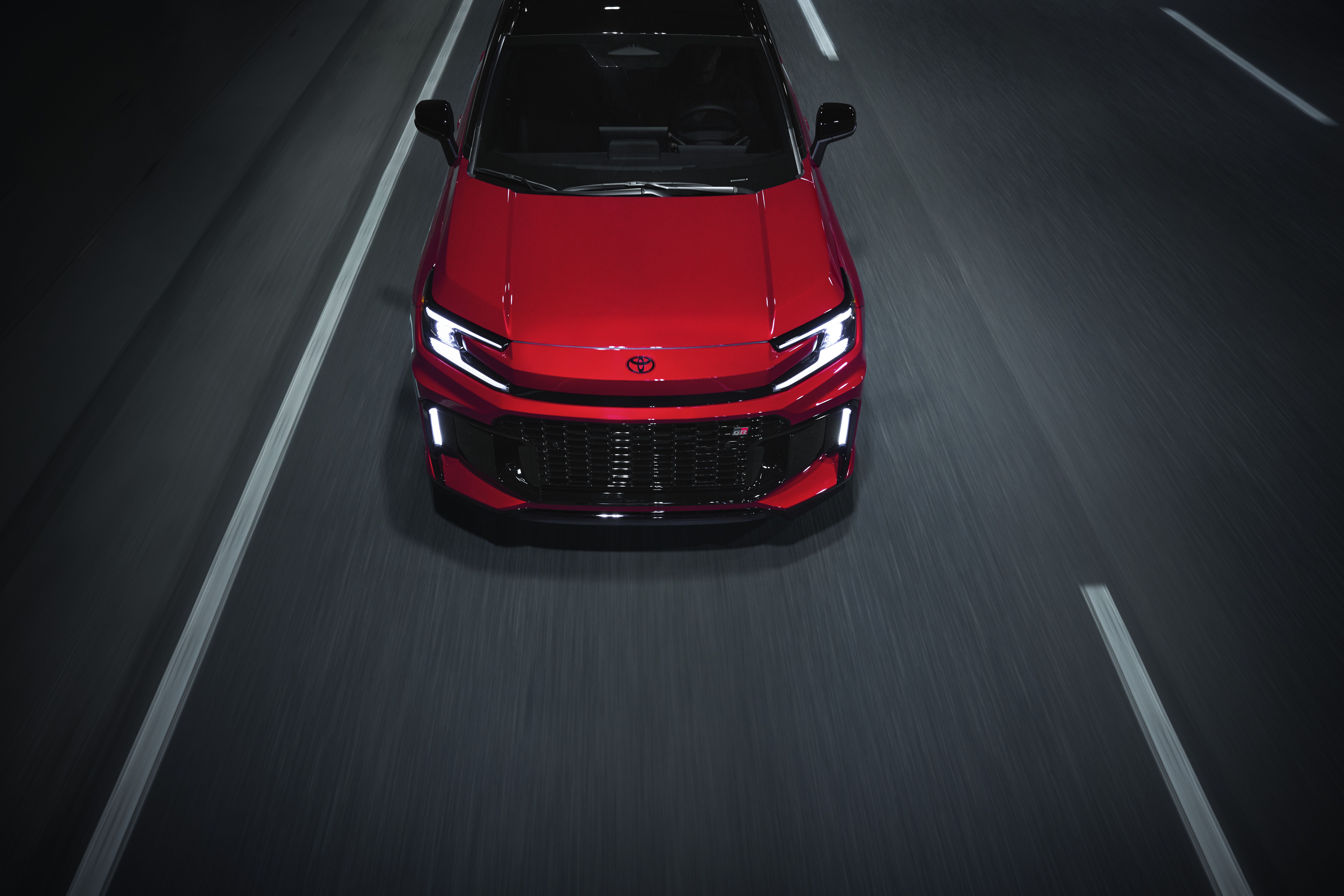 Red Toyota RAV4 drives on a black asphalt road