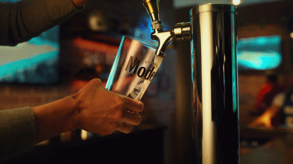 Pint of Modelo being poured, then cheersing with a bottle of Modelo in a bar.
