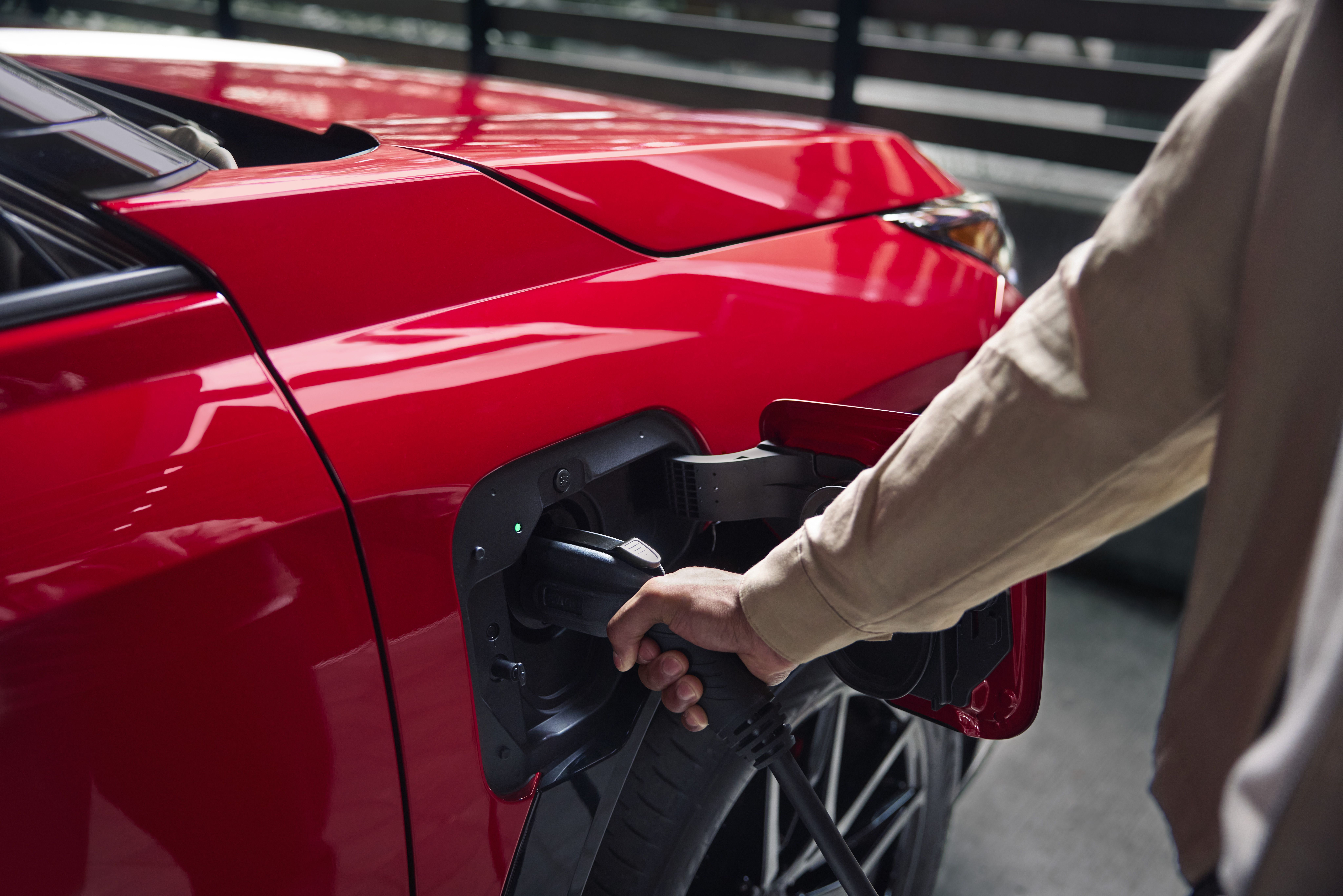 A person plugs in the charger of their red Toyota RAV4