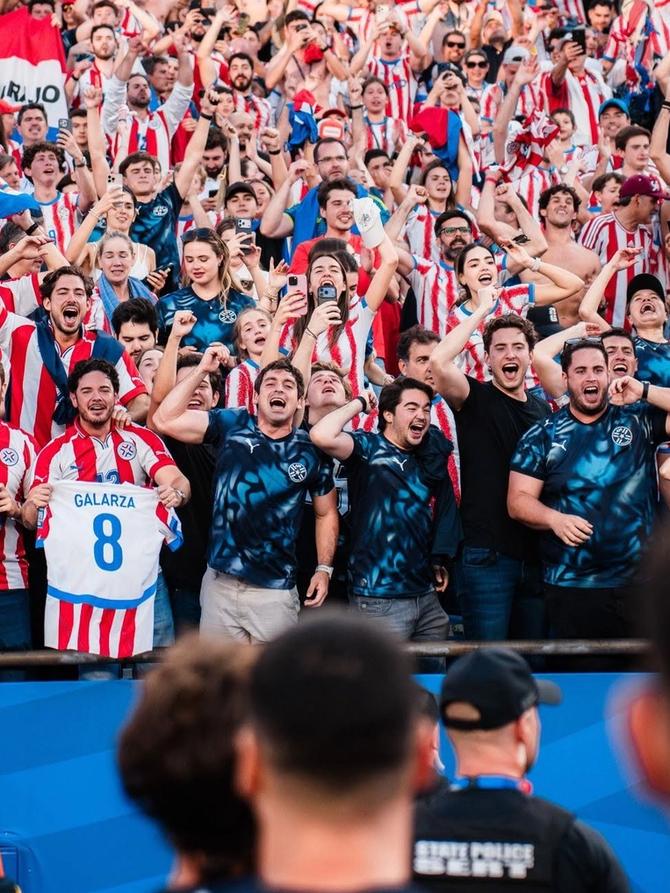 Players from the Paraguay national team walk towards celebrating fans.