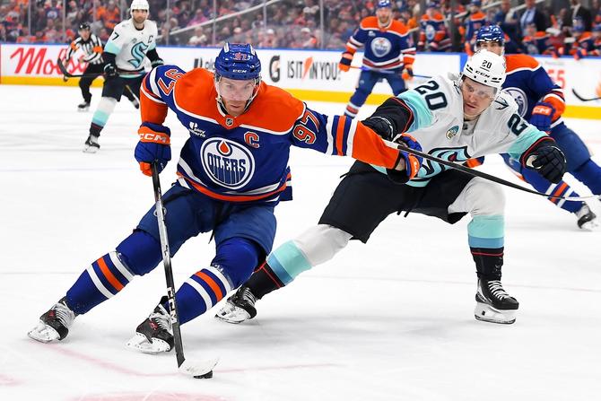 Edmonton Oiler Connor McDavid stick handles around the Seattle Kraken’s Eeli Tolvanen.