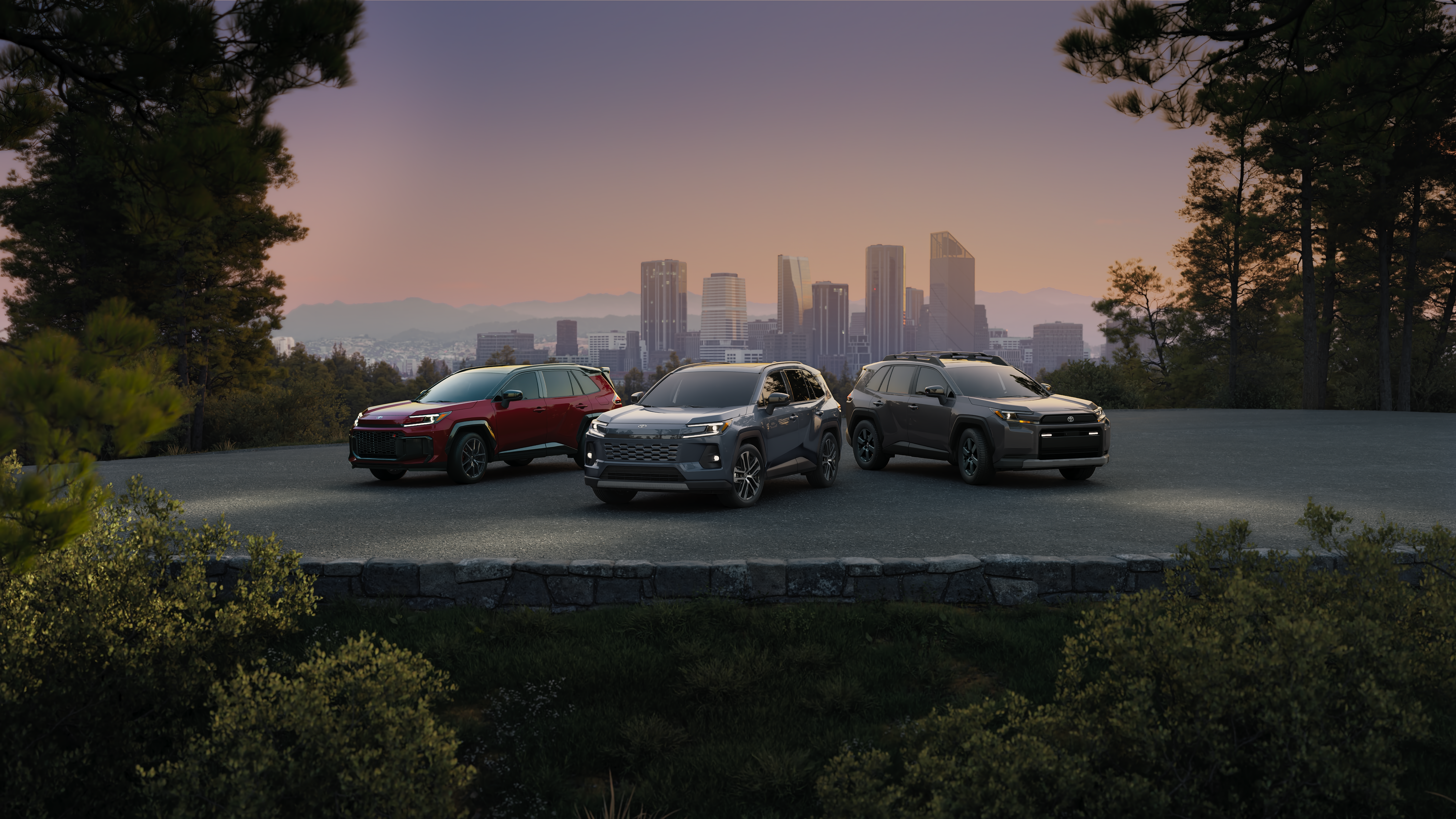 Three Toyota RAV4 SUVs parked at a scenic overlook at sunset, with a city skyline and tree-lined landscape in the background.