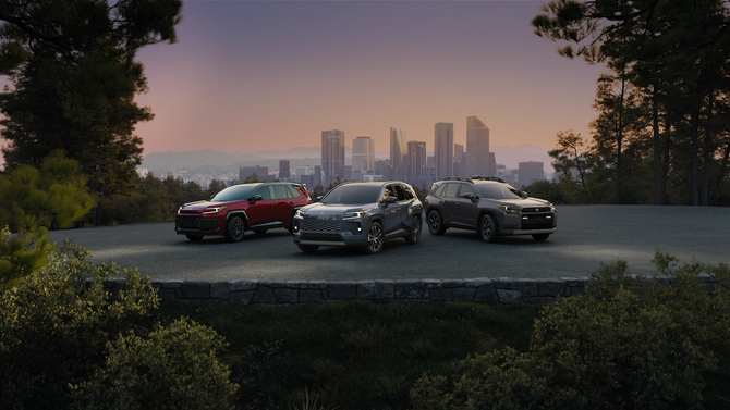 Three Toyota RAV4 SUVs parked at a scenic overlook at sunset, with a city skyline and tree-lined landscape in the background.
