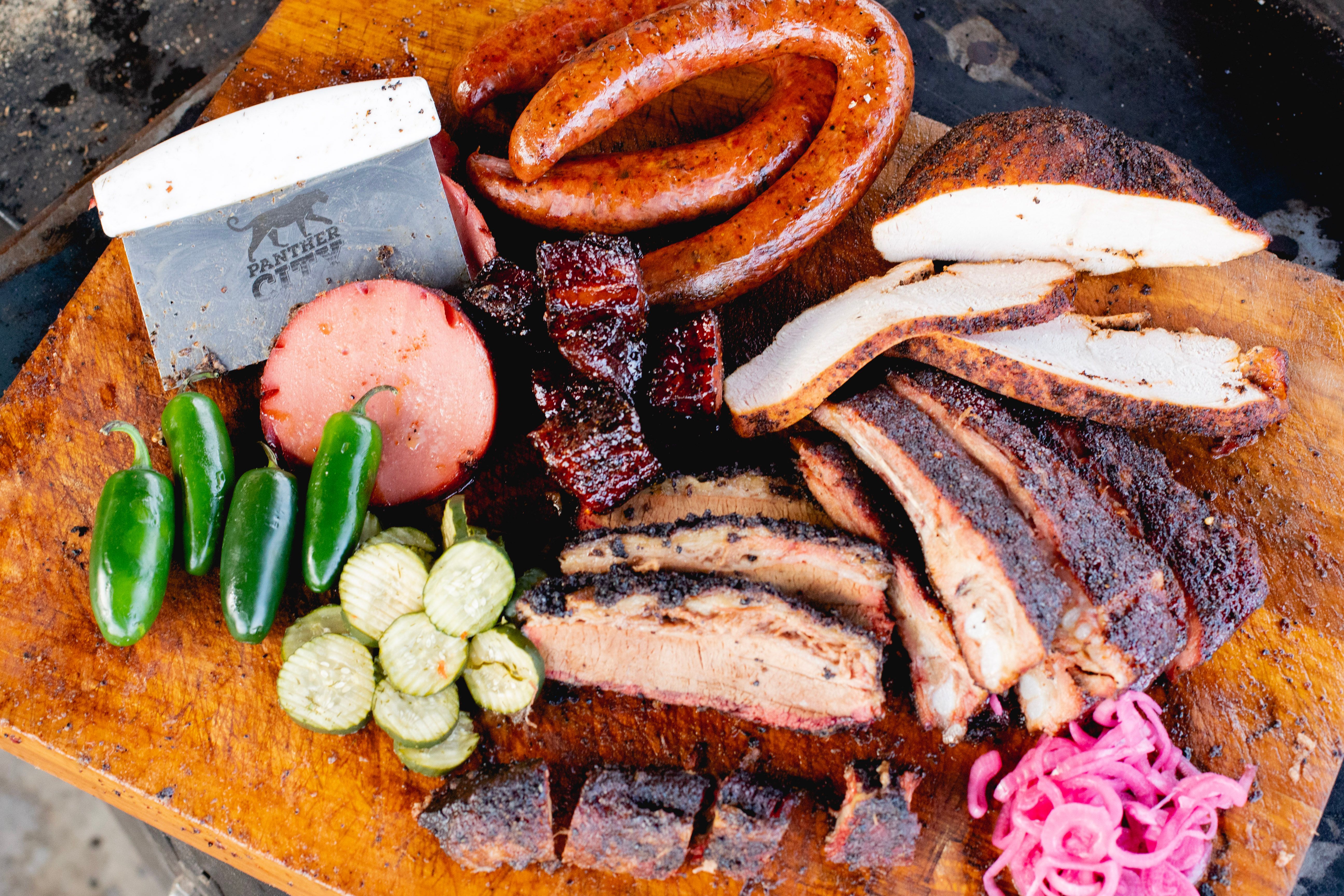 A platter features a selection of slow-smoked Texas barbecue, featuring signature brisket and savory sausages.