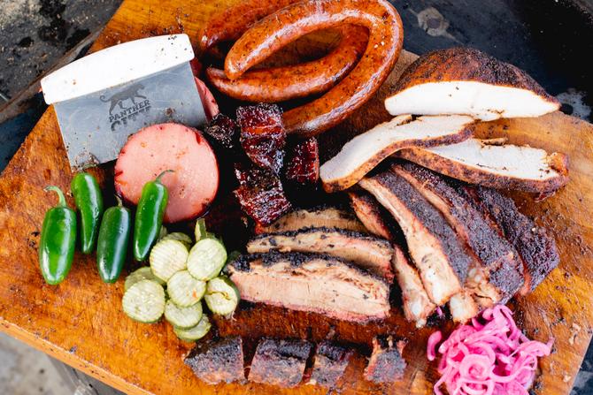 A platter features a selection of slow-smoked Texas barbecue, featuring signature brisket and savory sausages.