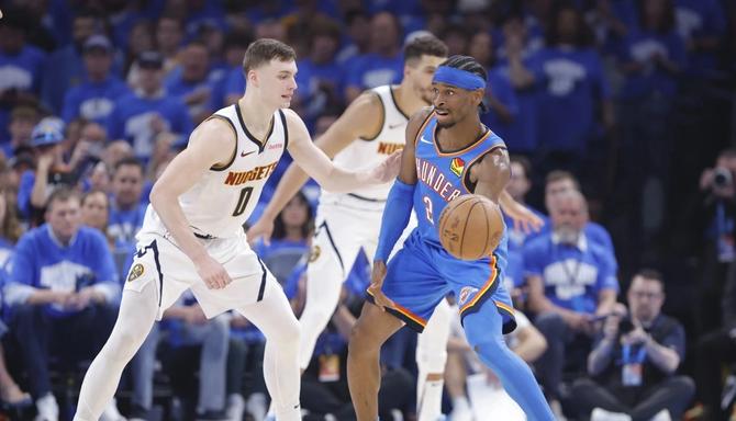 The OKC Thunder’s Shai Gilgeous-Alexander is defended by Denver Nugget Christian Braun.
