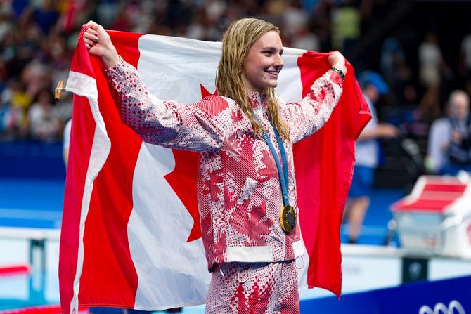 Team Canada swimmer Summer McIntosh poses with her gold medal and a Canadian flag after winning the women’s 200m individual medley on August 3, 2024.
