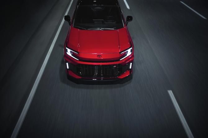 Red 2026 Toyota RAV4 driving on a dark road, viewed from above.