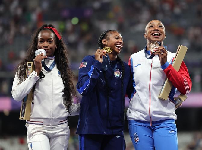 Gold medalist Masai Russell C of the United States, silver medalist Cyrena Samba-Mayela L of France and bronze medalist Jasmine Camacho-Quinn of Puerto Rico react during the victory ceremony of the women's 100m hurdles of Athletics at the Paris 2024 Olympic Games in Paris, France, Aug. 10, 2024.