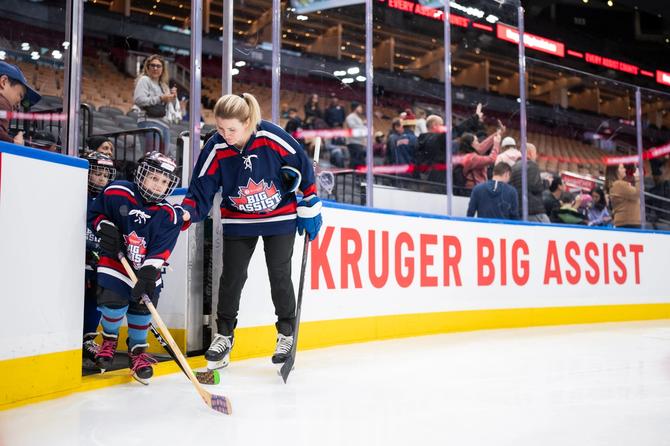 Hayley Wickenheiser helping a young hockey player onto the ice