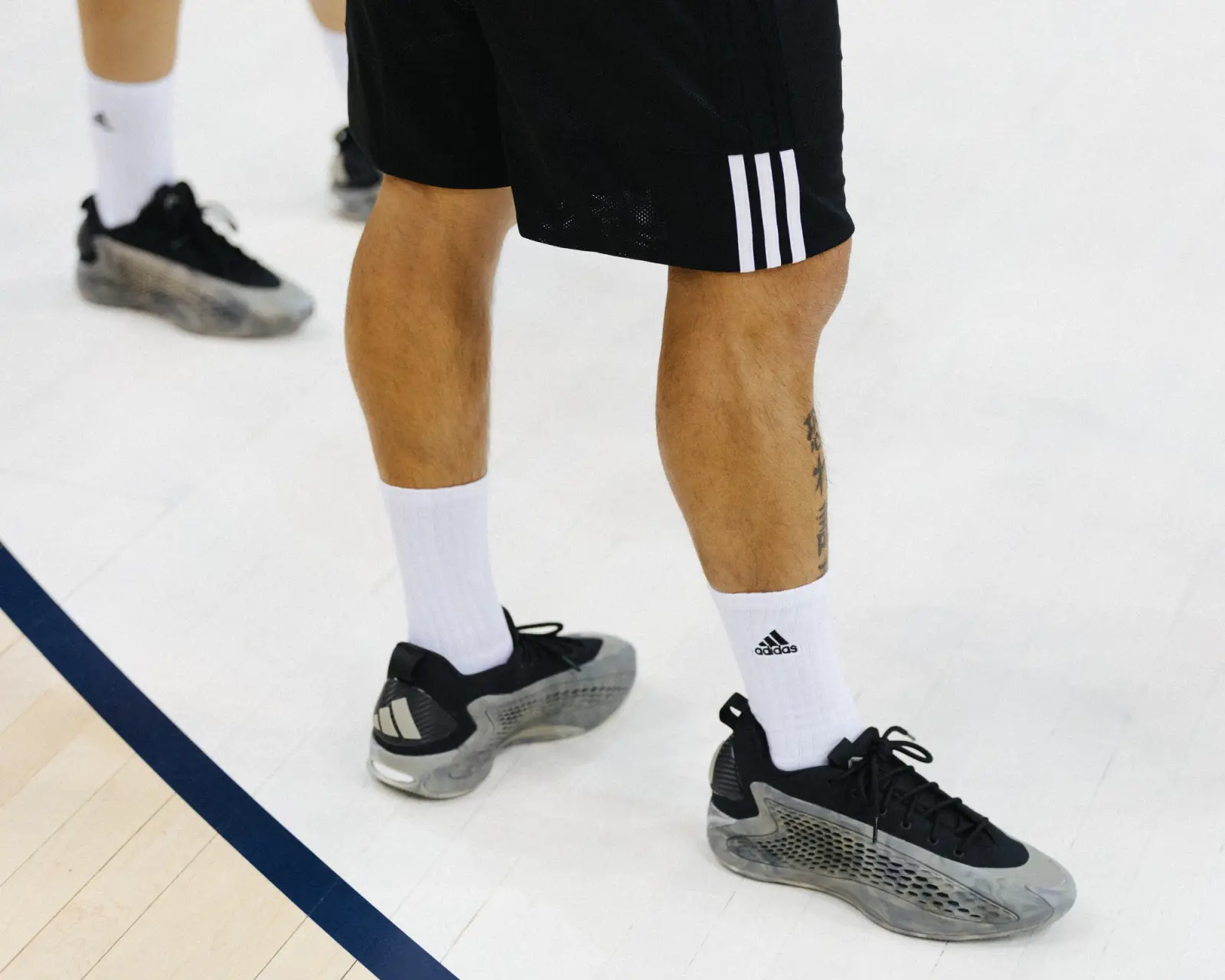 A close-up shot of a basketball player wearing adidas shorts, socks, and shoes