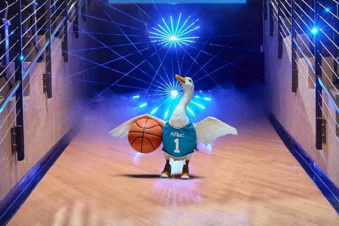 The Aflac duck holding a basketball on a basketball court