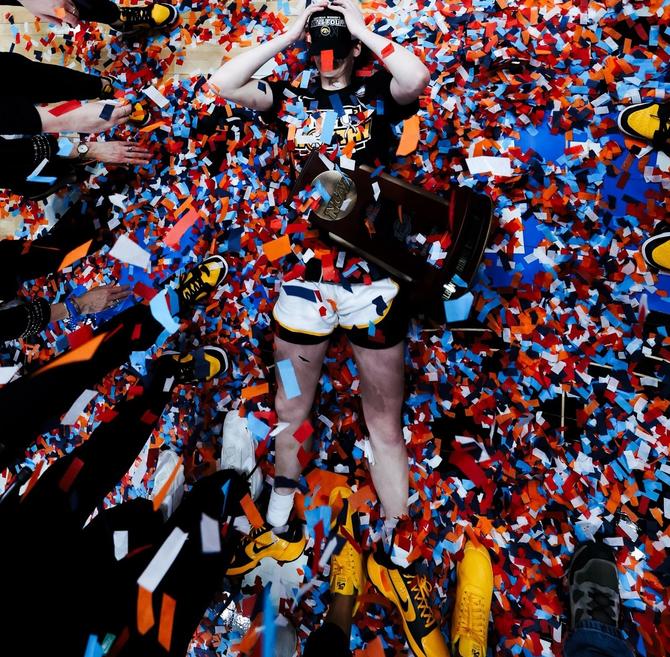 No. 1–seed Iowa women’s basketball star Caitlin Clark lies on the floor, covered in confetti and the NCAA regional championship trophy, after leading her Hawkeyes to Monday’s Elite Eight win over No. 3 LSU.