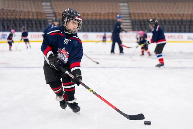 A young hockey playing handling a puck on the ice