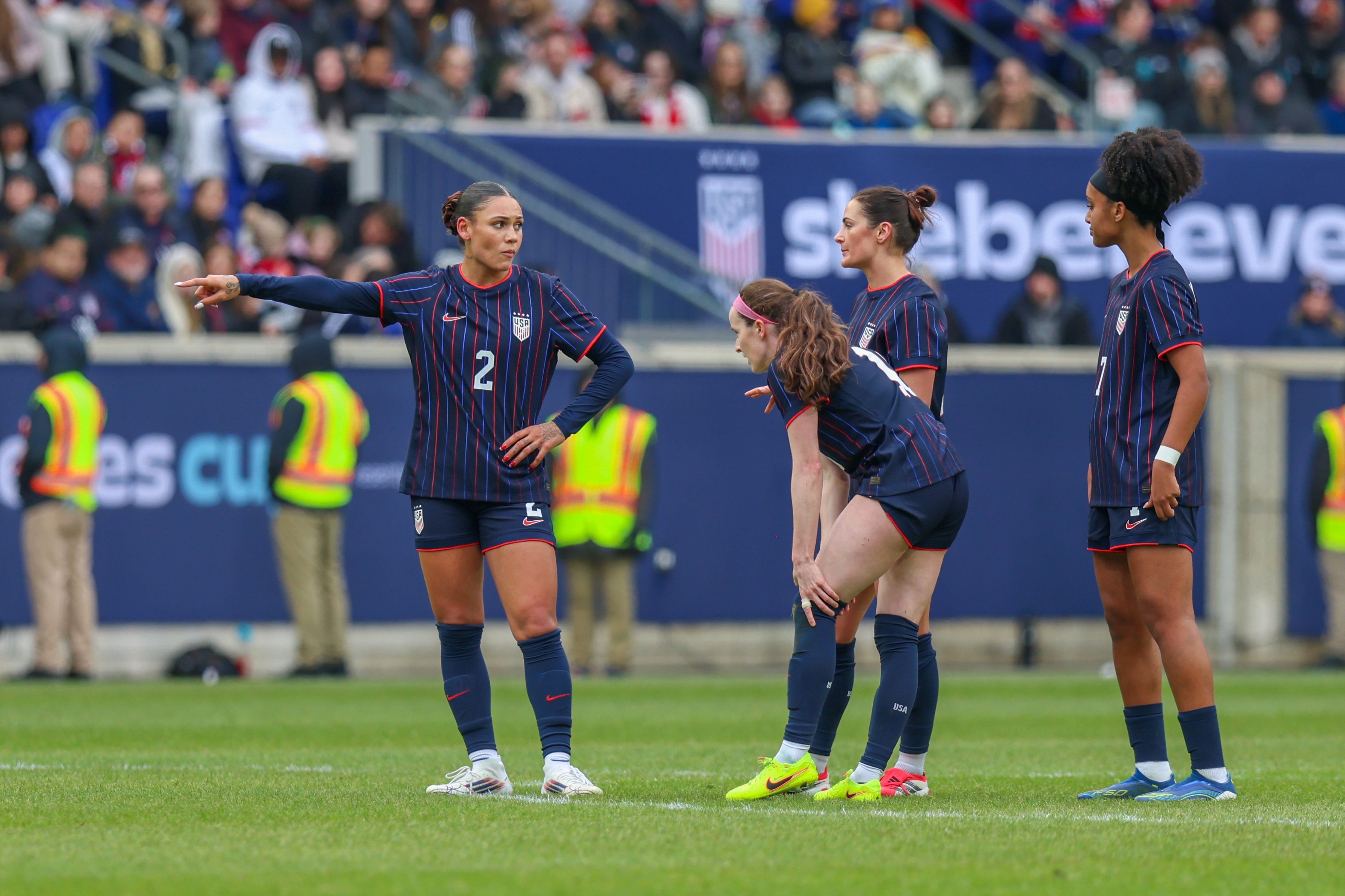 USWNT players Trinity Rodman, Rose Lavelle, Emily Fox, and Lily Yohannes talk during a stoppage in play.