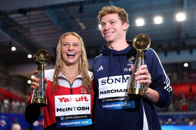 Summer McIntosh and Léon Marchand accept trophies for best swimmers of the meet at the World Aquatics Championship.