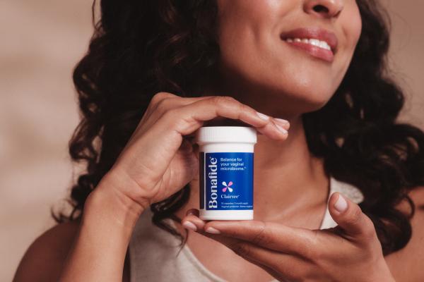 A close up of a woman holding a white container labelled with the Bonafide logo.