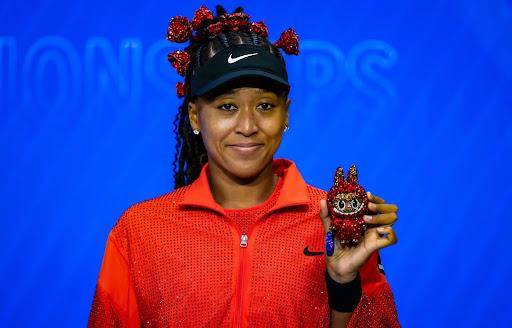 Tennis superstar Naomi Osaka holds up Billie Jean Bling after her opening match at the US Open.