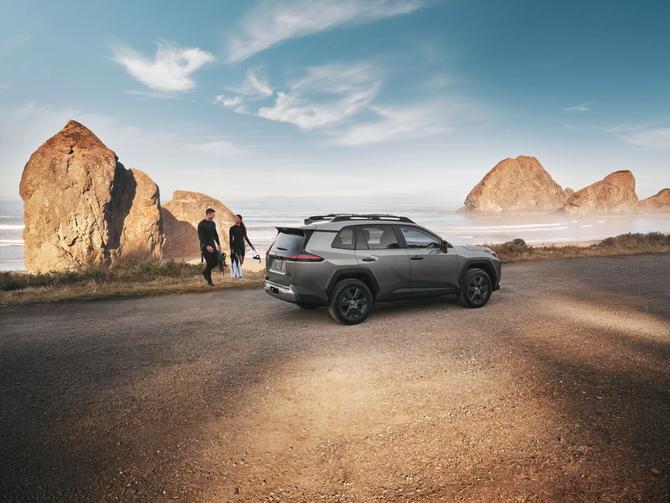 A Toyota RAV4 is parked on the beach while a couple heads to the water