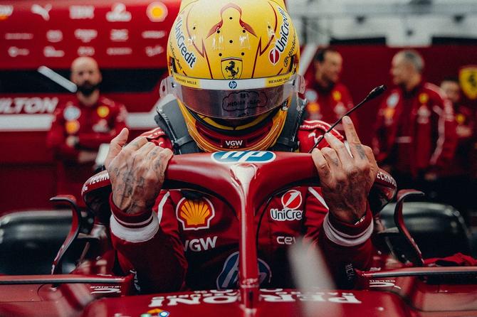 Ferrari’s Lewis Hamilton grabs the front of his car as he lowers himself into the cockpit.