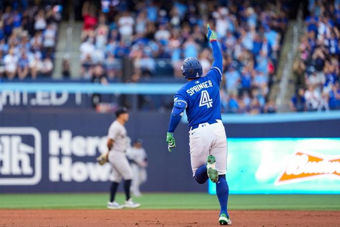 Toronto Blue Jay George Springer points upwards in celebration while rounding the bases after hitting a home run.