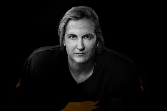 A black and white shot of Montréal Victoire captain Marie-Philip Poulin with orange Gatorade dripping down her face like sweat.