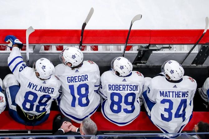 An overhead view of William Nylander, Noah Gregor, Nicholas Robertson, and Auston Matthews of the Toronto Maple Leafs looking on from the bench.