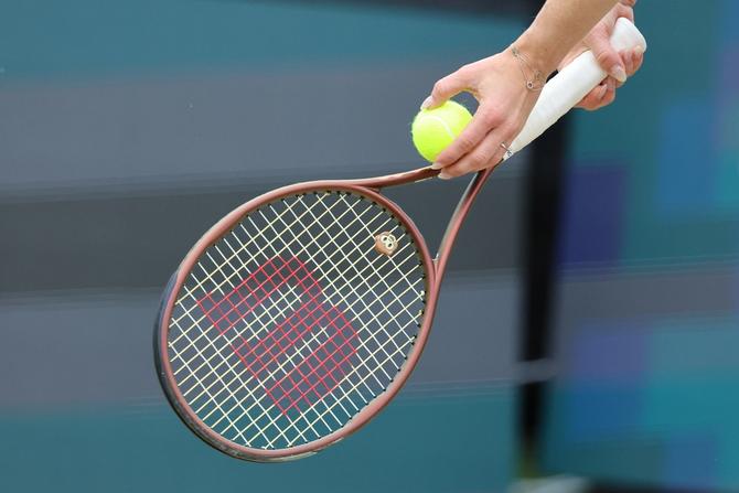 A woman prepares to serve the tennis ball.