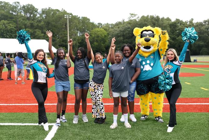 A group of people cheering together with the Jaguars mascot