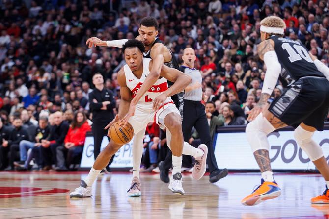 Toronto Raptor Scottie Barnes dribbles while San Antonio Spur Victor Wembanyama plays defense.