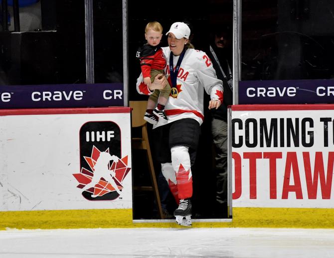 Natalie Spooner carrying a baby onto the ice
