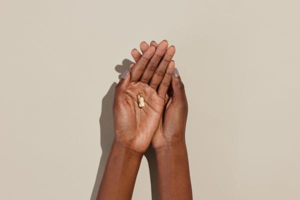 A woman holds out her two hands over a beige background; she is holding Bonafide's probiotic in her hands.